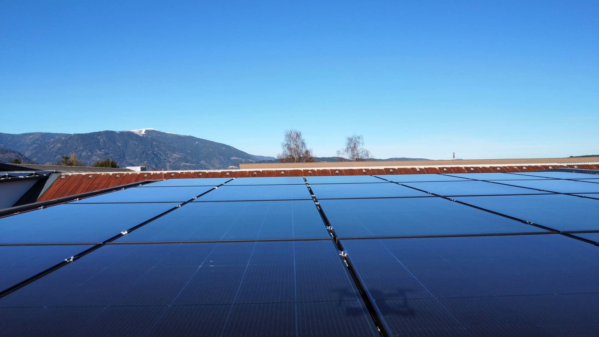 Drohnenaufnahme des Gewerbebetriebs in Oberösterreich mit Photovoltaik-Modulen in Ost-West-Ausrichtung auf dem Trapezblechdach