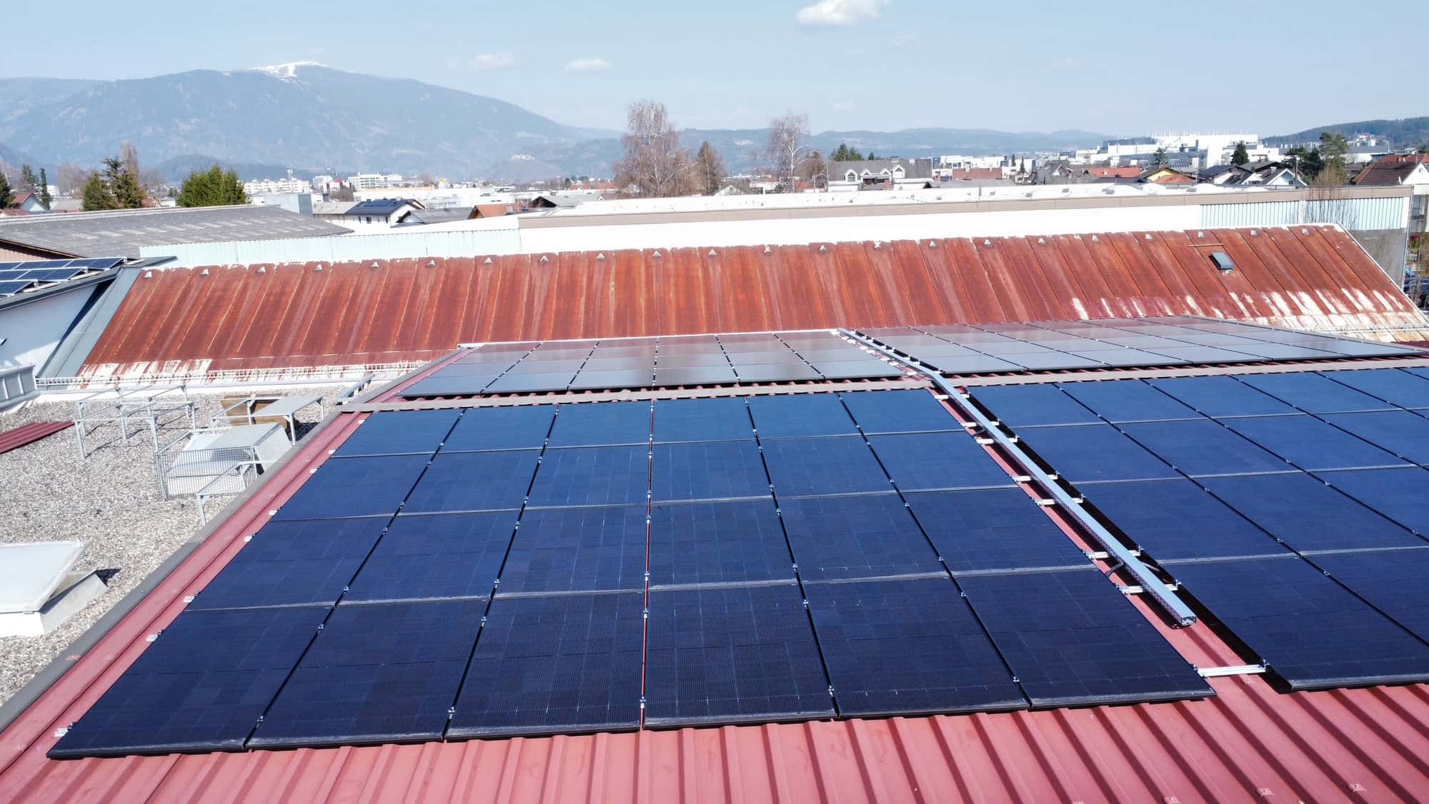 Nahaufnahme der Photovoltaik-Module auf dem Trapezblechdach mit Blick auf die Berge