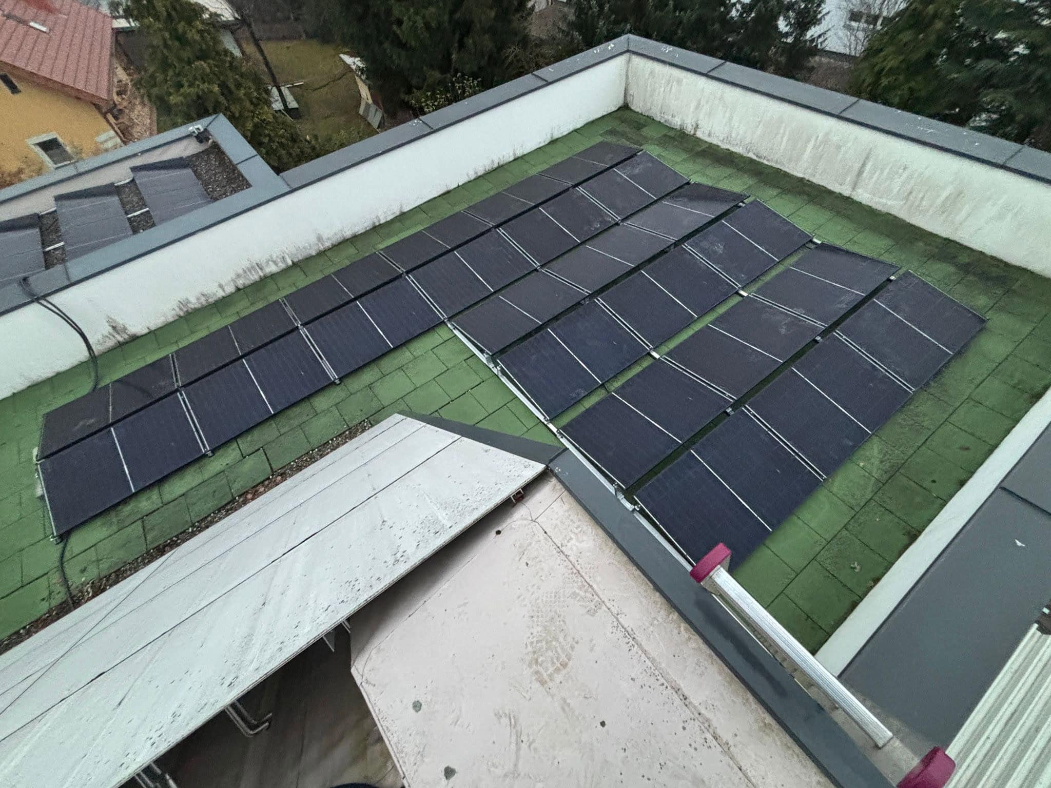 Aufgeständerte Glas-Glas-Module auf einem der Flachdächer des Stadthauses in Graz, ballastiert mit Betongewichten